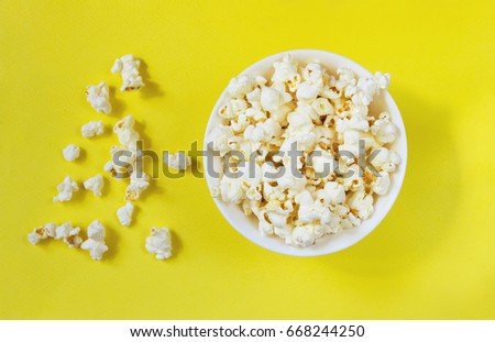 White popcorn in bowl on yellow background, ready-to-eat