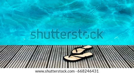 Swimming pool with fresh blue water and slippers on a wooden floor