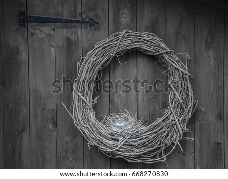 Picture of a Robin's nest with three blue eggs nestled in a woven vine wreath.