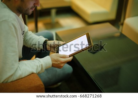 Businessman with digital tablet. Side view of confident young businessman in pullover working on digital tablet while sitting at the chair