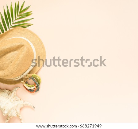 Summer fashion, summer outfit on cream background. Seashell, wood bracelet and straw hat. Flat lay, top view.