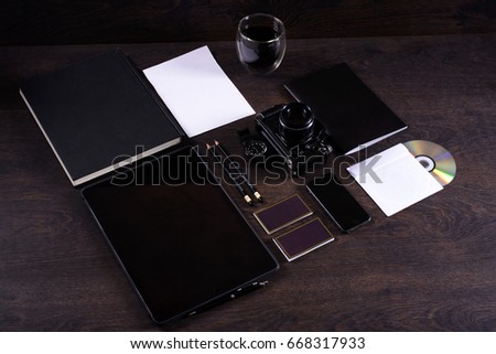 photo camera , coffee mug ,phone,business cards,notebook, pencils, sheet of paper, on dark brown background of the table