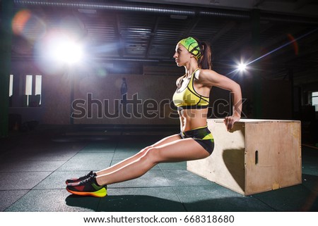 Young, strong muscular girl jumps in the gym to the elevation. Leg training and cardio inside