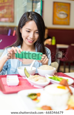 Young Woman taking photo on her dish in restaurant