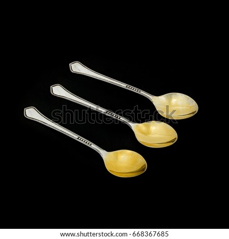 Three silver dessert spoons with gilding on a black background
