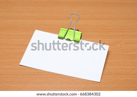 blank white business card with green binder clip on the wooden office desk