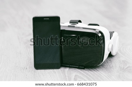 VR Glasses or Virtual Reality Headset helmet with phone wood background