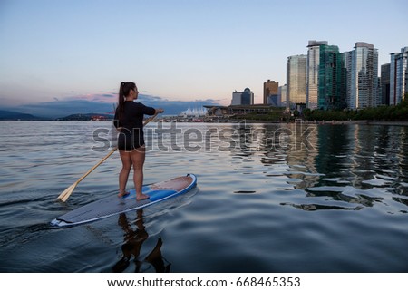 Girl on a stand up paddle board in Coal Harbour, Downtown Vancouver, British Columbia, Canada. Taken during a beautiful sunset.