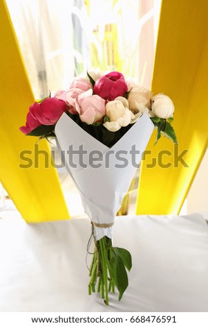 Bouquet of beautiful colorful peony flowers on leather chair in room
