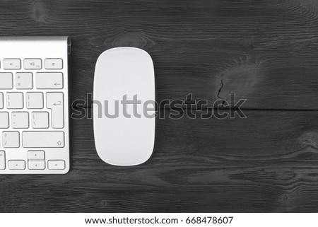 Close up view of a business workplace with wireless computer keyboard, mouse and keys on old black wooden table background
