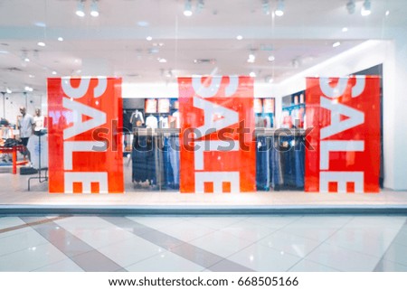 Blurred big sales on Black Friday. On sale at a clothing store in a modern shopping mall  beautiful lobby at the malls. Big sales. Big bright red banners with the sale sign