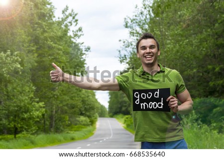 Hitchhiking. A man with a sign standing on the road."Good mood"