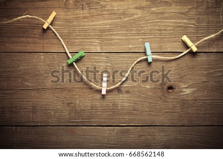 Colored clothespins on rope on a wooden table or board for background. Space for text. Toned.