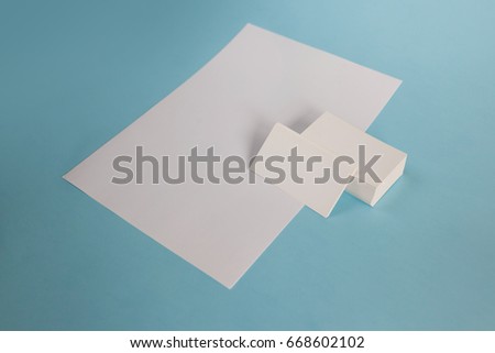 White paper A4 and a business card on a blue background. Brochure mockup. Blank white business cards on blue background