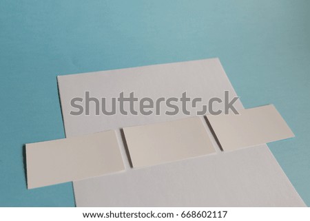 White paper A4 and a business card on a blue background. Brochure mockup. Blank white business cards on blue background