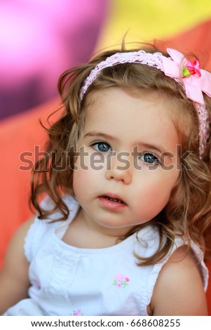 Portrait of a sweet one year old girl  against blurred bright colorful background