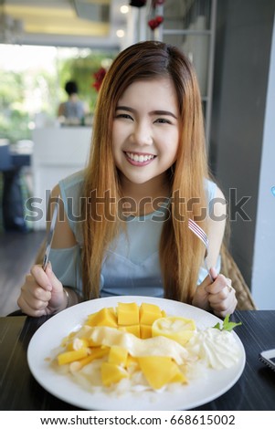 Beautiful Asian girl enjoy eating Crepes cake in coffee shop cafe