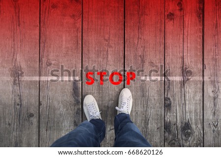 Man standing on the wooden boards with red colored stop message on the floor, point of view perspective used. Royalty-Free Stock Photo #668620126