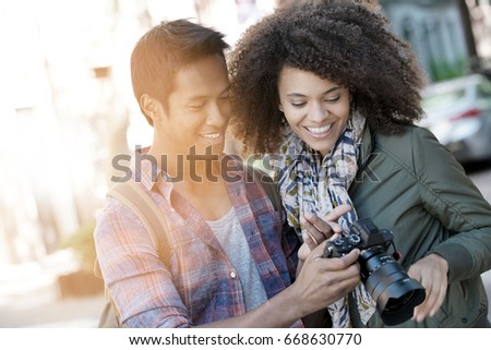 Man showing pictures to girlfriend on camera screen    