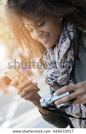 Woman photographer transfering files from camera to smartphone