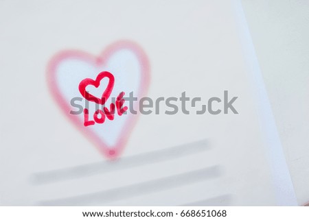 the hole in the white card  in the form of a heart. through the hole you can see the word love. the focus is on this message, heart. Wedding card. romantic mood, empty space for text