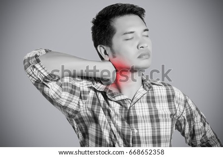 young man holding his back in pain. monochrome photo with red as a symbol for the hardening. isolated on gray background.