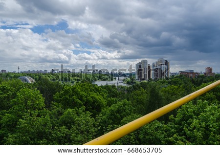The view from the Ferris wheel at green park. Under construction skyscrapers on the horizon. The sense of height above the trees.
