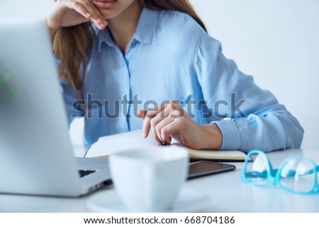 Young woman working at the computer at the desk in the office.