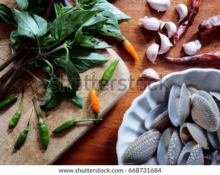 Top table view picture of the ingredients for clam fried garlic and chili with sweet basil on  wooden table.