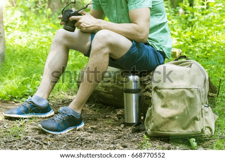 A young man takes photos of nature in the woods