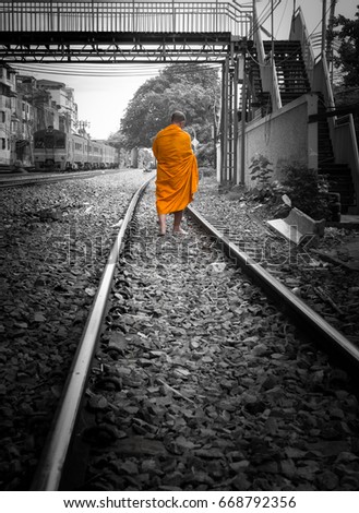 Buddhist Thai monk walking along railway without shoes to temple, colored monk with separated black and white photo