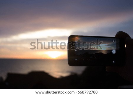 Smartphones take pictures of the sea at sunset.