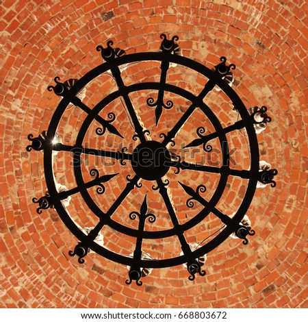 Medieval vintage chandelier silhouette on red brick background (square)