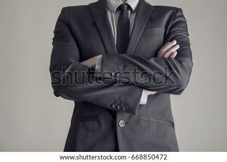 Torso of a businessman standing with folded arms in a classic black suit, vintage effect toned image. Royalty-Free Stock Photo #668850472