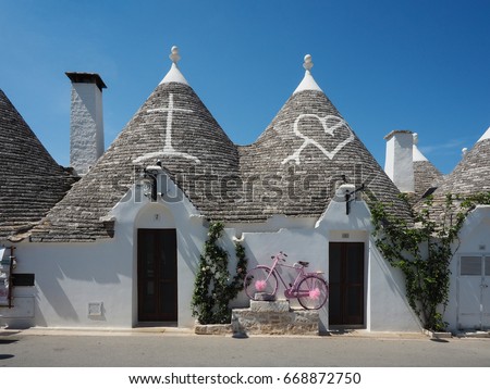 Beautiful town of Alberobello with trulli houses among green plants and flowers, main touristic district, Apulia region, Southern Italy
