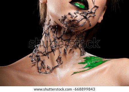 Model with decorative creative fashion make up on black background in studio photo. Cosmetics and extravagant makeup