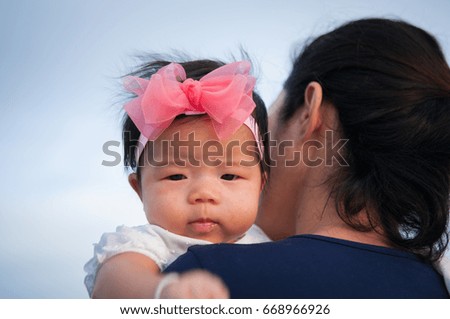 Mother day bonding concept with newborn baby nursing. Mother is holding newborn baby with flower pink headband with blue sky. Focus at infant girl
