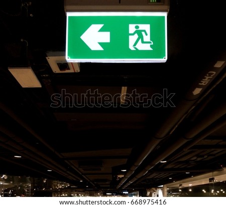emergency exit sign in a shopping mall. open loft bear ceiling design showing infrastructure pipeline  