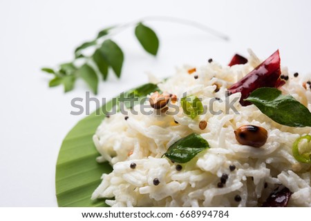 Curd Rice / Dahi Chawal OR Bhat with curry leaf, peanuts and chilli- Served over coconut leaf over moody background. Selective focus