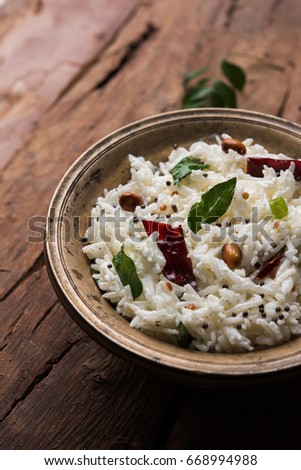 Curd Rice / Dahi Bhat OR Chawal with curry leaf, peanuts and chilli- Served in a bowl over moody background. Selective focus