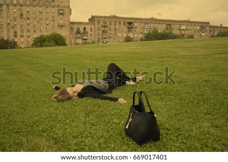 business girl with a bag lying in the Park on the grass