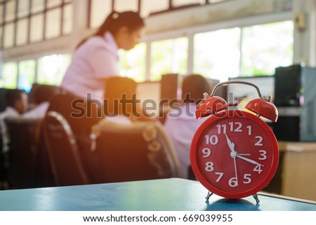 Close up red alarm clock and blur background, Teachers are teaching students to use computers in computer labs. Technology is essential in everyday life. Student at school in Thailand. 