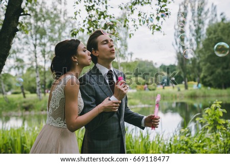 The bride and groom blow bubbles in the park