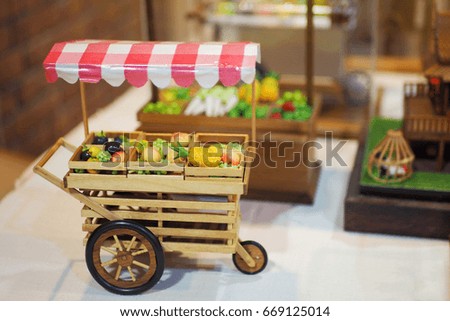 Shopping cart for fruit miniature, wooden room background.