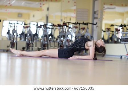 Girl practicing yoga in studio. Attractive female doing mat exercise and posing in modern bright fitness center.