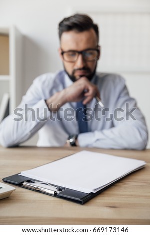 selective focus of pensive businessman looking at blank papers on table