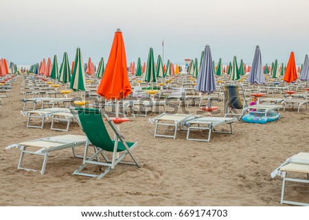 Beach with closed umbrellas and sunbeds in the evening in Lignano Italy
