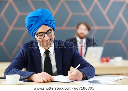 Arabian newsreader making notes in his notebook in studio