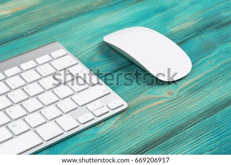 Business workplace with computer, wireless keyboard and mouse on old blue wooden table background. Office desk with copy space