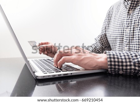 Man's hand holds credit card and another one enters data on laptop